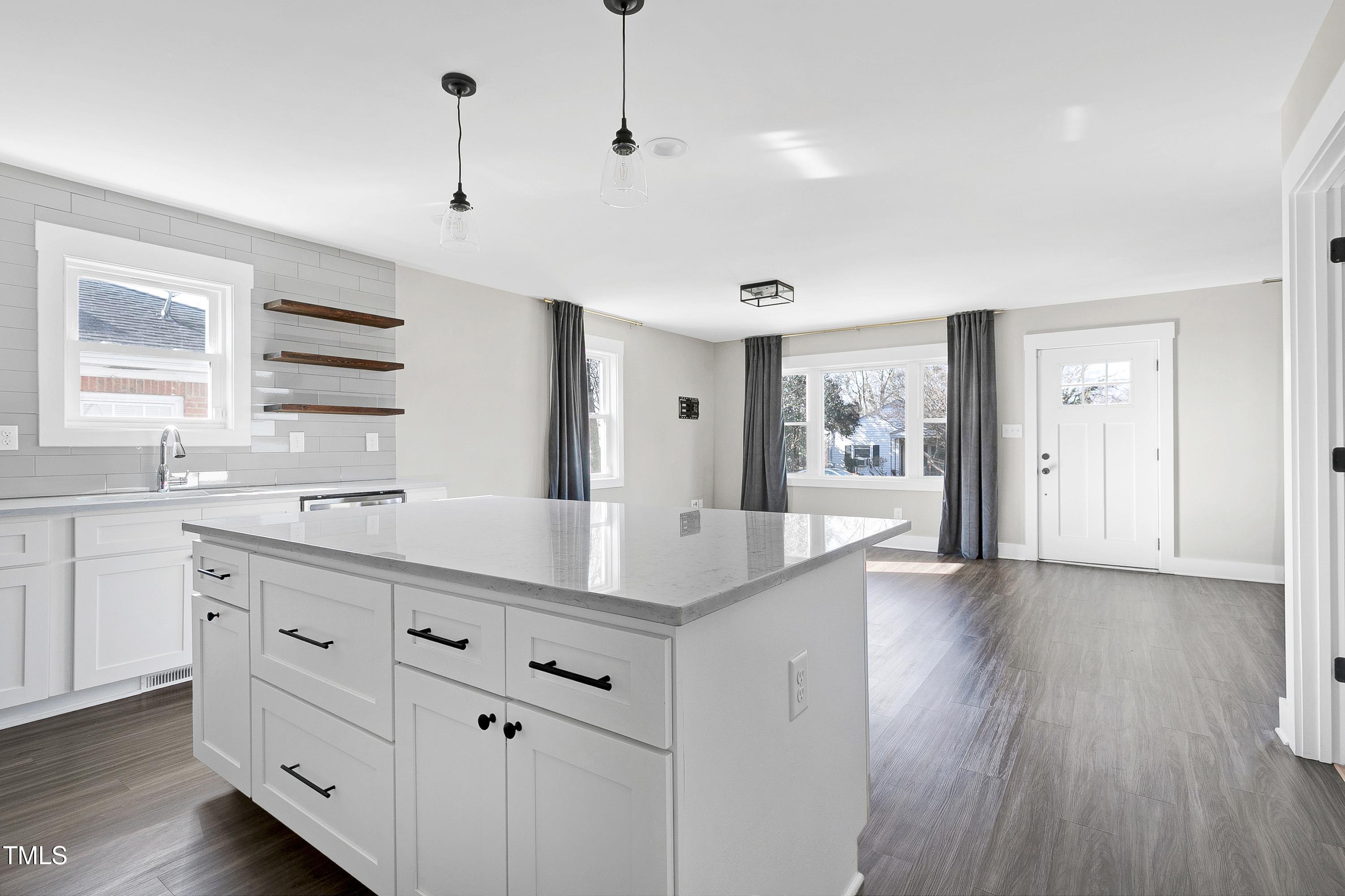 621 Coleman Street Raleigh, NC 27610 - Photo 11 of 42 a hall with kitchen island white cabinets and wooden floor