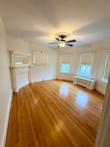 a view of an empty room with a window and wooden floor