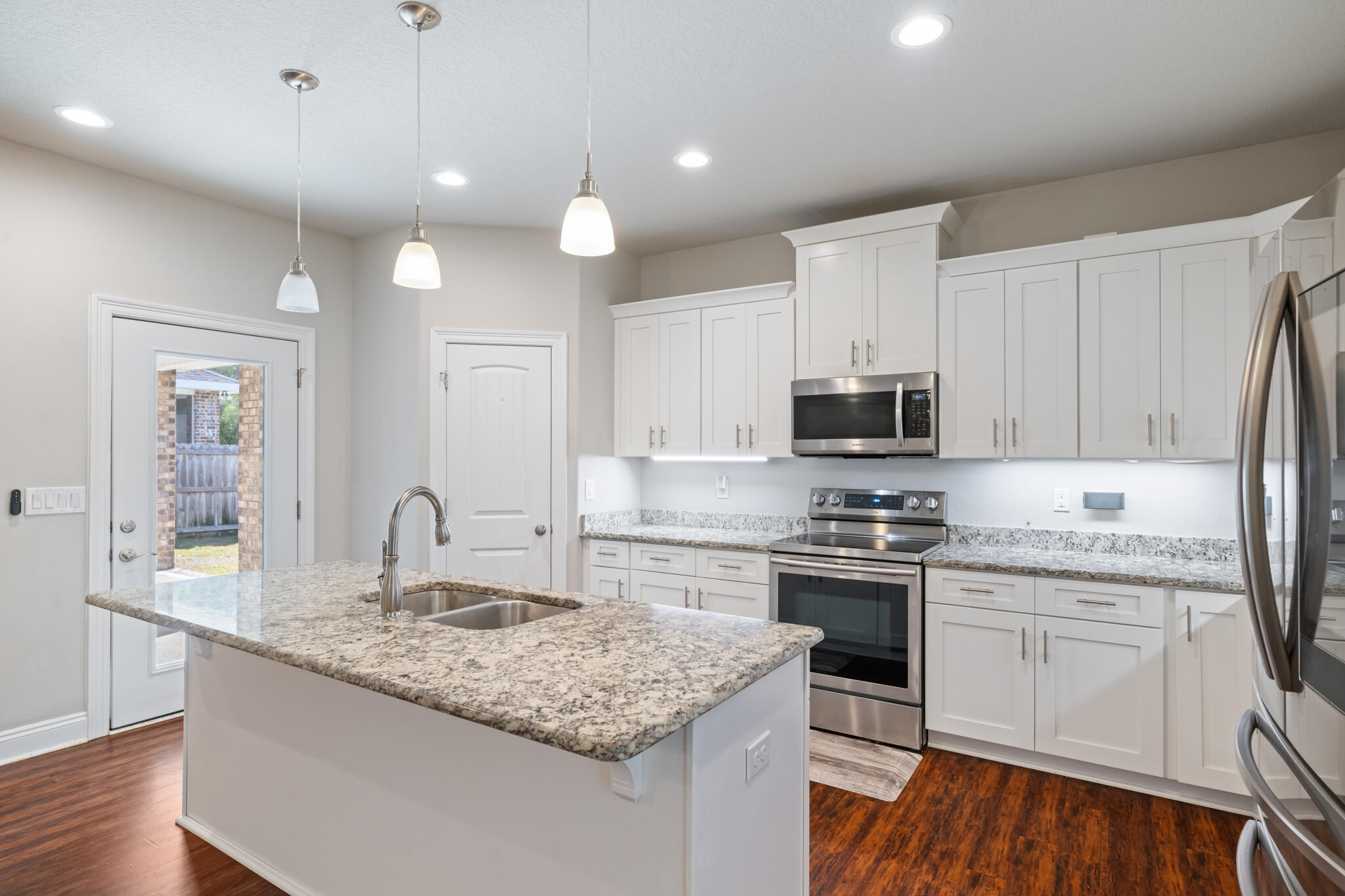 7287 Gordon Evans Road Navarre, FL 32566 - Photo 19 of 45 a kitchen with kitchen island granite countertop a sink stainless steel appliances and white cabinets