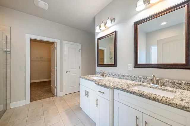 a bathroom with a granite countertop double vanity sink and a mirror