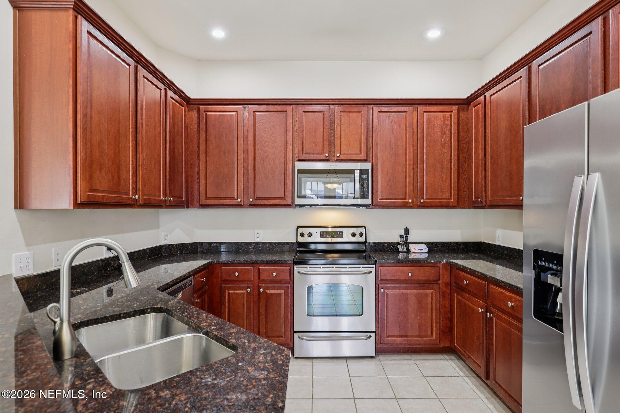 2035 Secret Garden Lane, Unit 505 Fleming Island, FL 32003 - Photo 15 of 47 a kitchen with stainless steel appliances granite countertop a sink stove refrigerator and cabinets