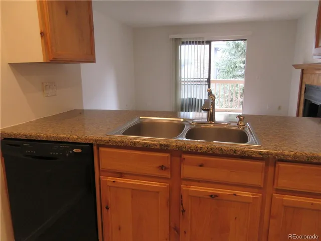 a kitchen with granite countertop a sink dishwasher and cabinets with wooden floor