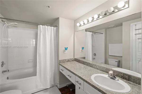a bathroom with a granite countertop sink a mirror and a shower