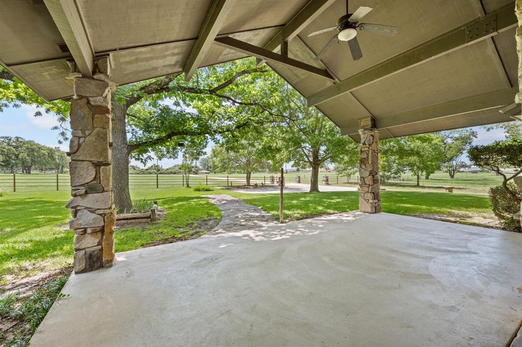 515 New Highland Road Springtown, TX 76082 - Photo 5 of 38 Covered patio featuring a ceiling fan, concrete flooring, and stone-clad support columns