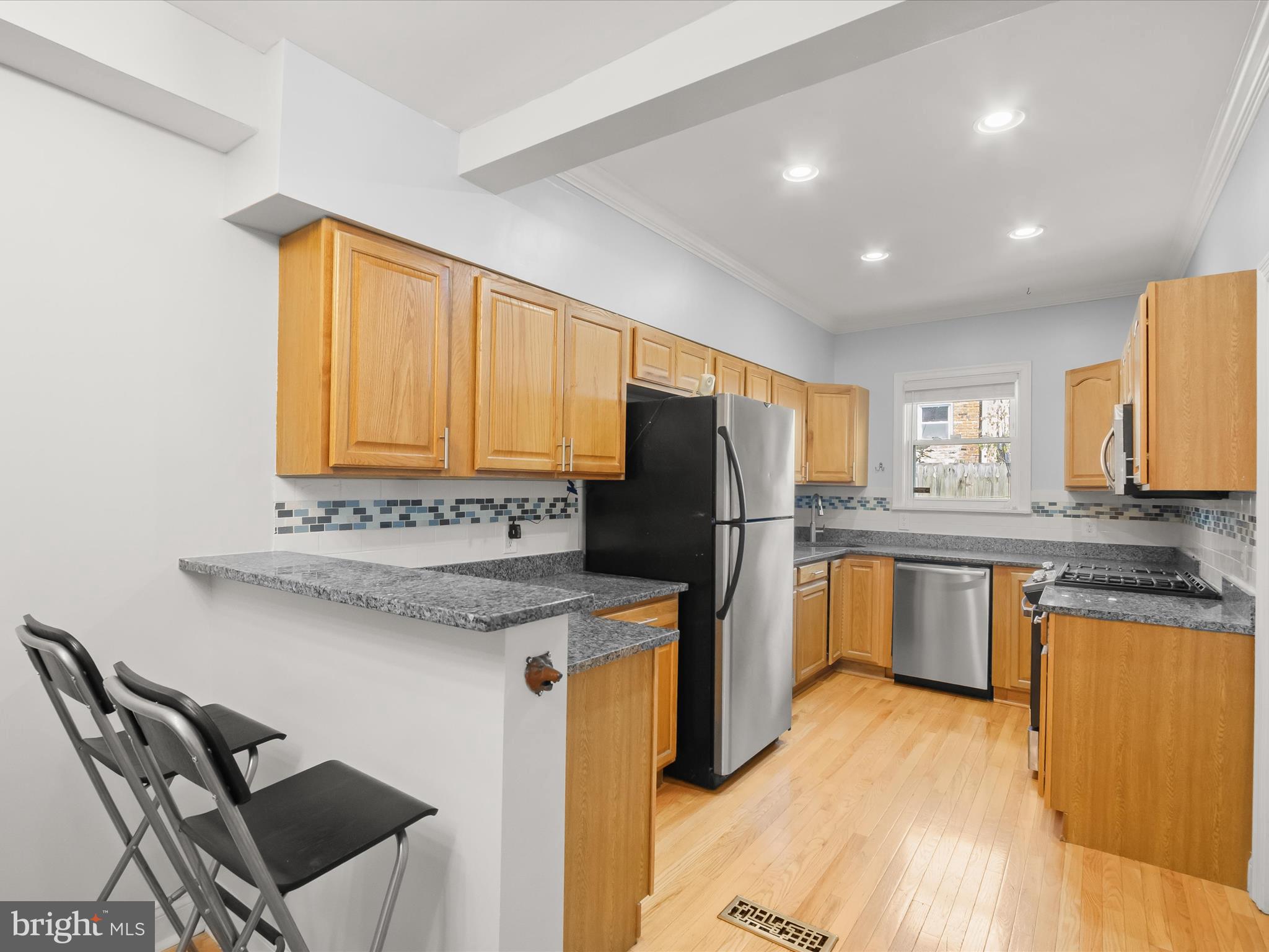 1648 Kramer Street Northeast Washington, DC 20002 - Photo 7 of 30 a kitchen with stainless steel appliances granite countertop a refrigerator a sink dishwasher a stove with chairs and wooden floor