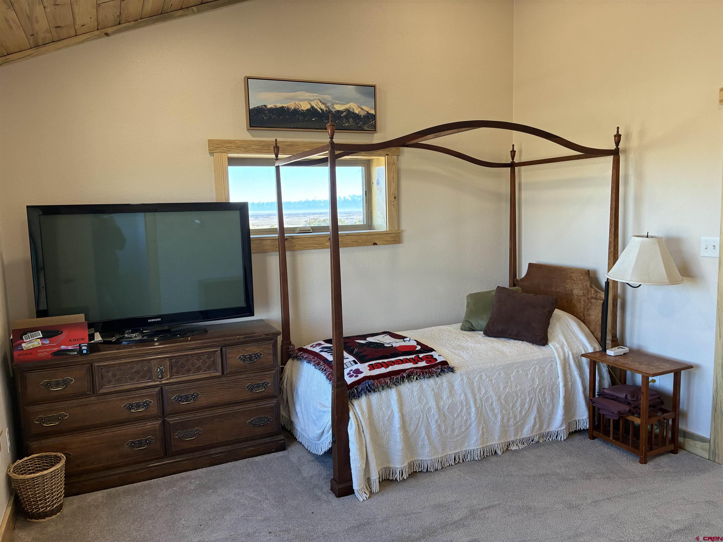 180 Boulder Lake Road Monte Vista, CO 81144 - Photo 18 of 35 a bedroom with a bed and a flat tv screen on dresser