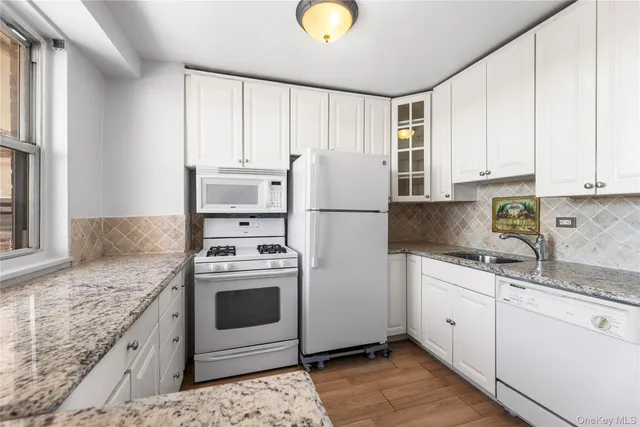 a kitchen with granite countertop white cabinets and white appliances