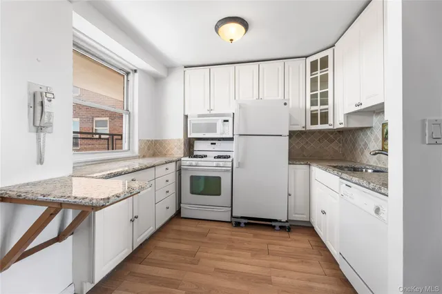a kitchen with granite countertop white cabinets and white appliances