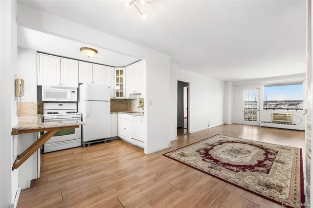 a kitchen with stainless steel appliances granite countertop a stove top oven a refrigerator a sink and white cabinets with wooden floor