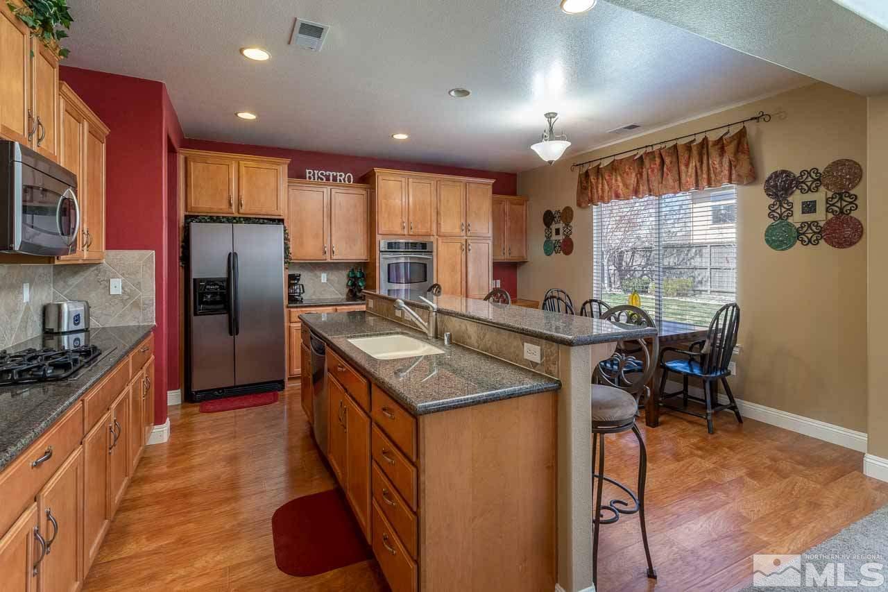 621 Steeplechase Court Reno, NV 89521 - Photo 7 of 18 a kitchen with stainless steel appliances granite countertop sink stove top oven and refrigerator