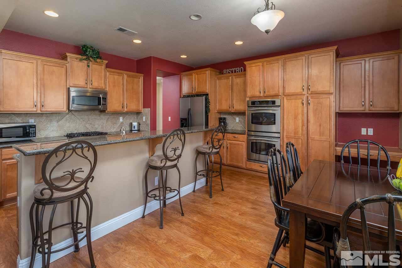621 Steeplechase Court Reno, NV 89521 - Photo 8 of 18 a kitchen with granite countertop a table chairs microwave and cabinets