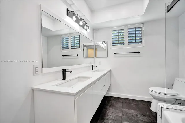 a bathroom with a double vanity sink toilet and a mirror