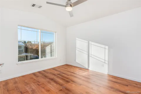 a view of empty room with wooden floor and fan