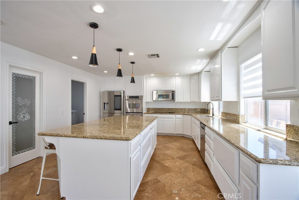 23126 Teil Glen Road Wildomar, CA 92595 - Photo 11 of 48 a view of a kitchen with kitchen island a large counter top space a sink stainless steel appliances and windows