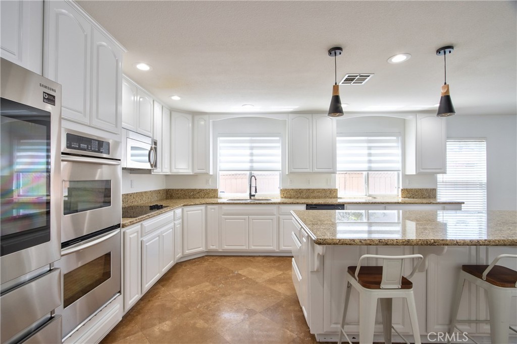 23126 Teil Glen Road Wildomar, CA 92595 - Photo 13 of 48 a kitchen with stainless steel appliances granite countertop a stove sink and microwave