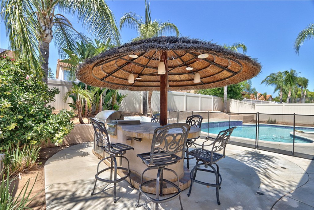23126 Teil Glen Road Wildomar, CA 92595 - Photo 37 of 48 a view of patio with chairs and table under an umbrella with a barbeque