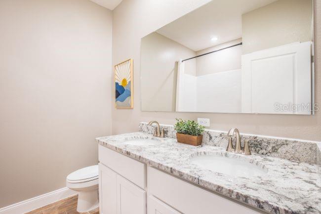16492 Crane Road Weeki Wachee, FL 34614 - Photo 18 of 24 a bathroom with a granite countertop sink a toilet and a mirror