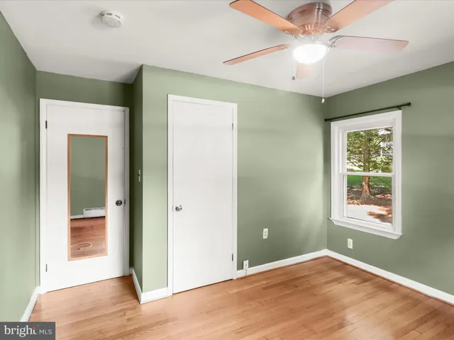 an empty room with wooden floor and fan