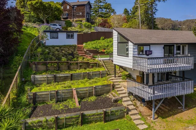 a view of house with a deck and a yard with green space