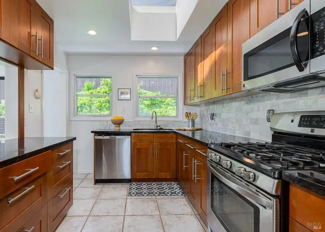 a kitchen with stainless steel appliances granite countertop a stove a sink and a microwave