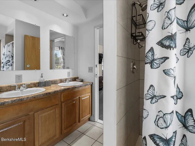 a bathroom with a granite countertop sink a mirror and shower