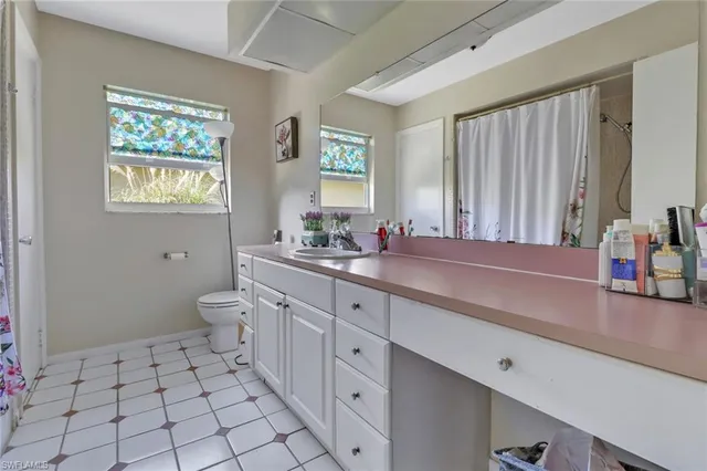 a spacious bathroom with a double vanity sink a mirror and a toilet