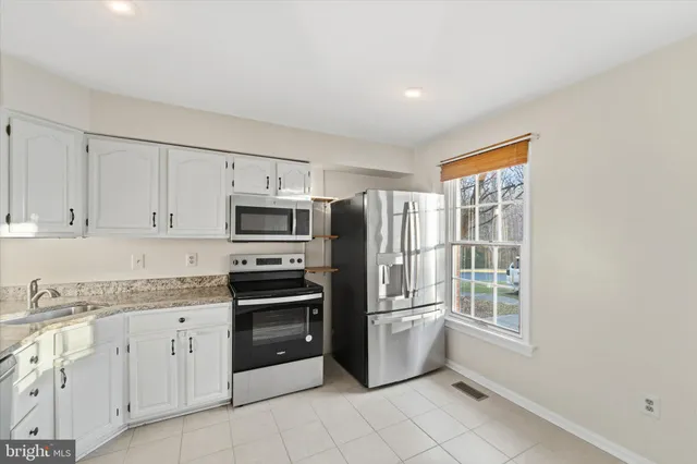 a kitchen with granite countertop a refrigerator and cabinets
