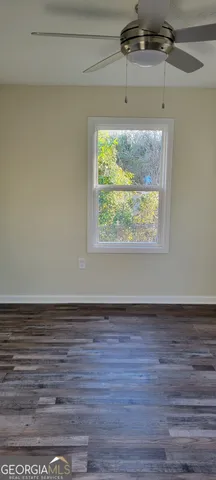 a view of empty room with window and wooden floor
