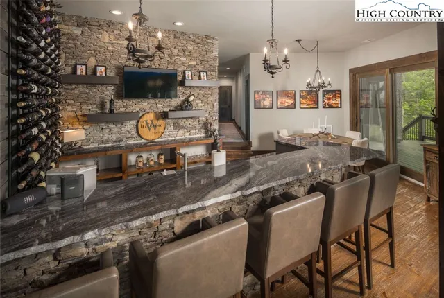 a kitchen with stainless steel appliances granite countertop a stove top oven a dining table and chairs with the floor to ceiling window