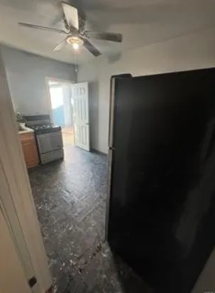 a view of a hallway to an empty room with wooden floor and a ceiling fan