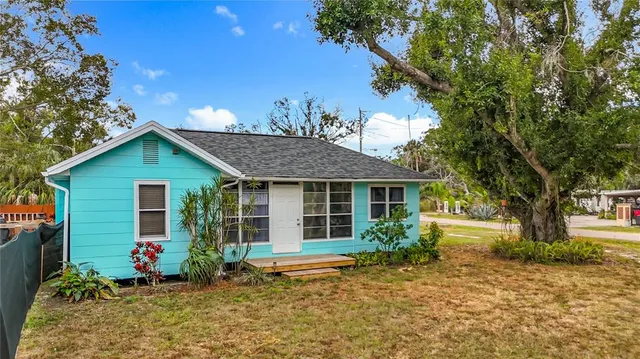a view of a house with a small yard and a large tree
