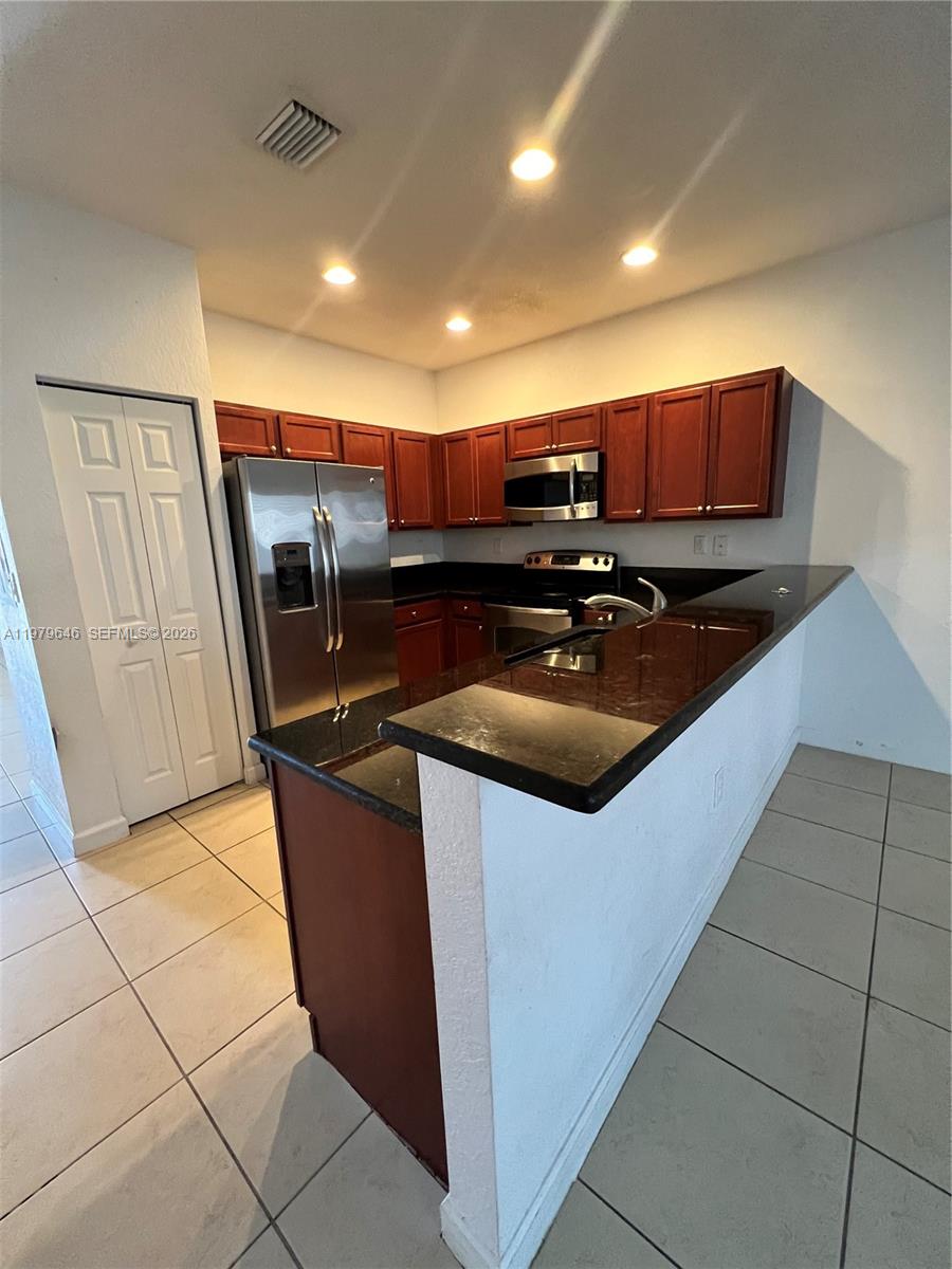 9031 Southwest 227th Street, Unit 2 Cutler Bay, FL 33190 - Photo 3 of 16 a kitchen with stainless steel appliances granite countertop a sink a stove a microwave a counter top and a cabinets