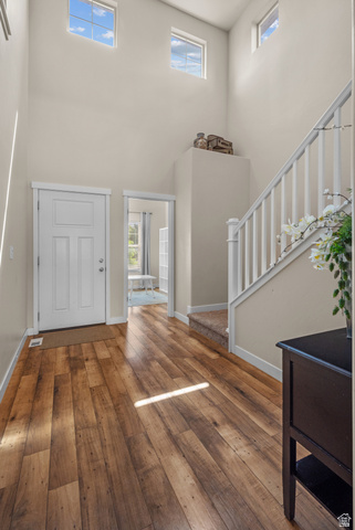 955 Delorean Lane Midvale, UT 84047 - Photo 4 of 47 Two-story entryway featuring wood-finish flooring, a white paneled entry door, a carpeted staircase, and high transom windows