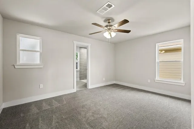 an empty room with windows and fan