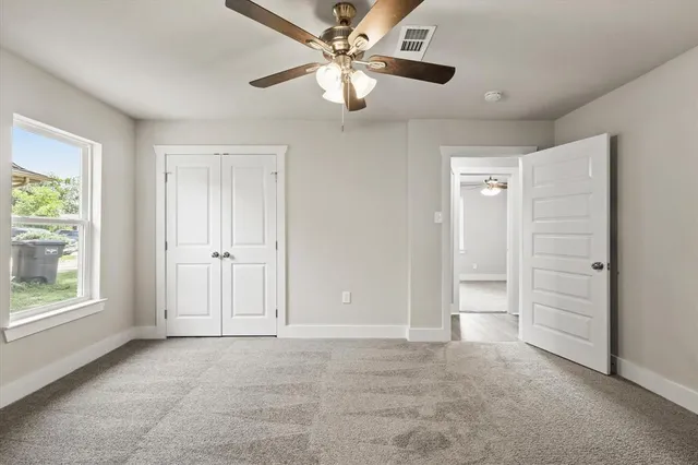 an empty room with windows and fan