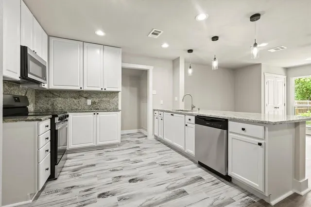 a large kitchen with cabinets wooden floor and stainless steel appliances