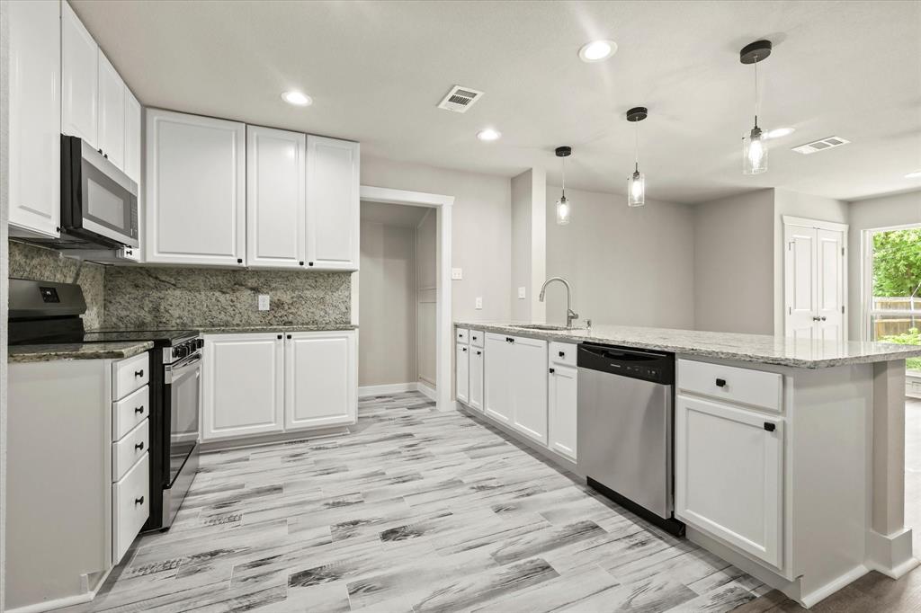 5629 Maceo Lane Fort Worth, TX 76112 - Photo 18 of 25 a large kitchen with cabinets wooden floor and stainless steel appliances