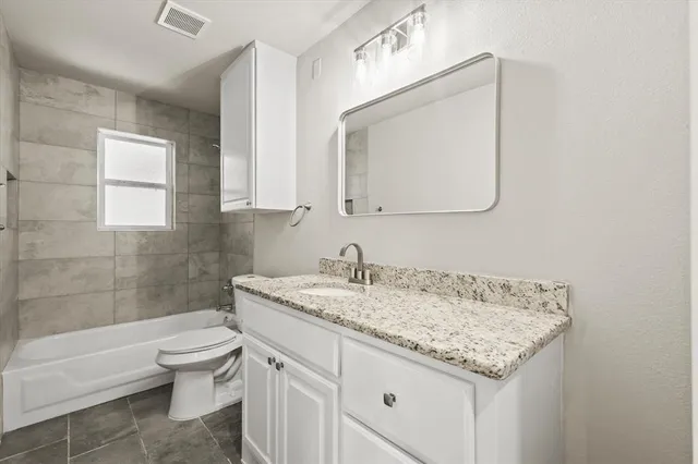 a bathroom with a granite countertop sink a toilet and a bathtub
