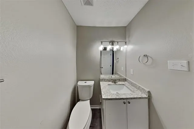 a bathroom with a granite countertop toilet sink and mirror