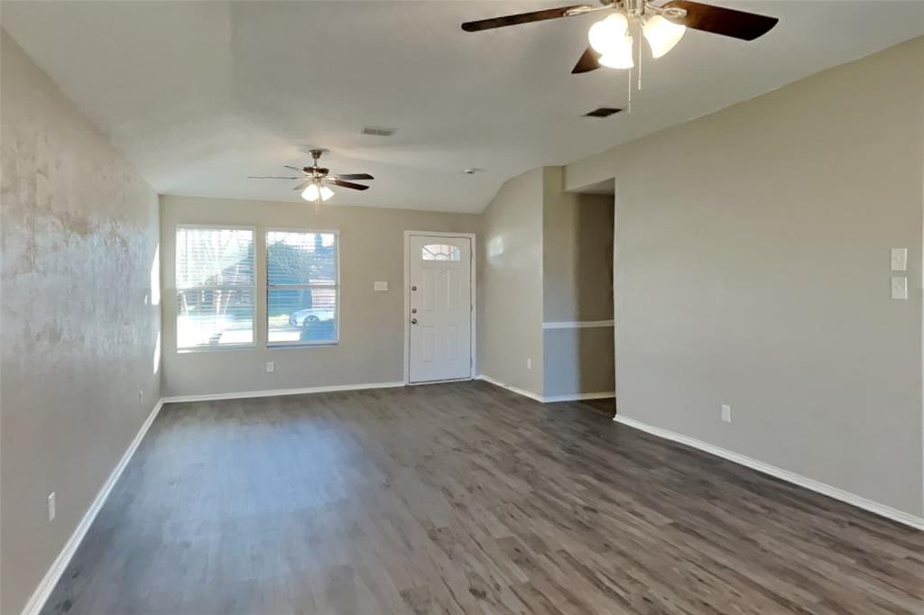 516 Bailey Street Saginaw, TX 76179 - Photo 3 of 19 an empty room with wooden floor chandelier fan and windows
