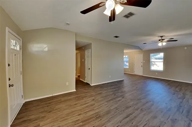 a view of an empty room with a window and wooden floor