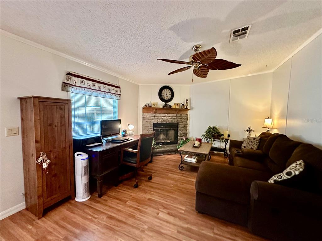56233 Water Oak Road Astor, FL 32102 - Photo 19 of 50 a living room with furniture a fireplace and a ceiling fan