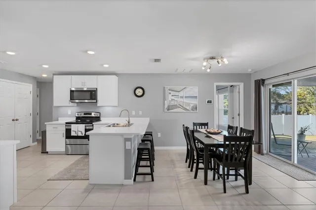 a kitchen with stainless steel appliances granite countertop a stove top oven a sink a dining table and chairs with wooden floor