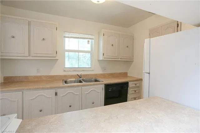 a kitchen with white cabinets and sink