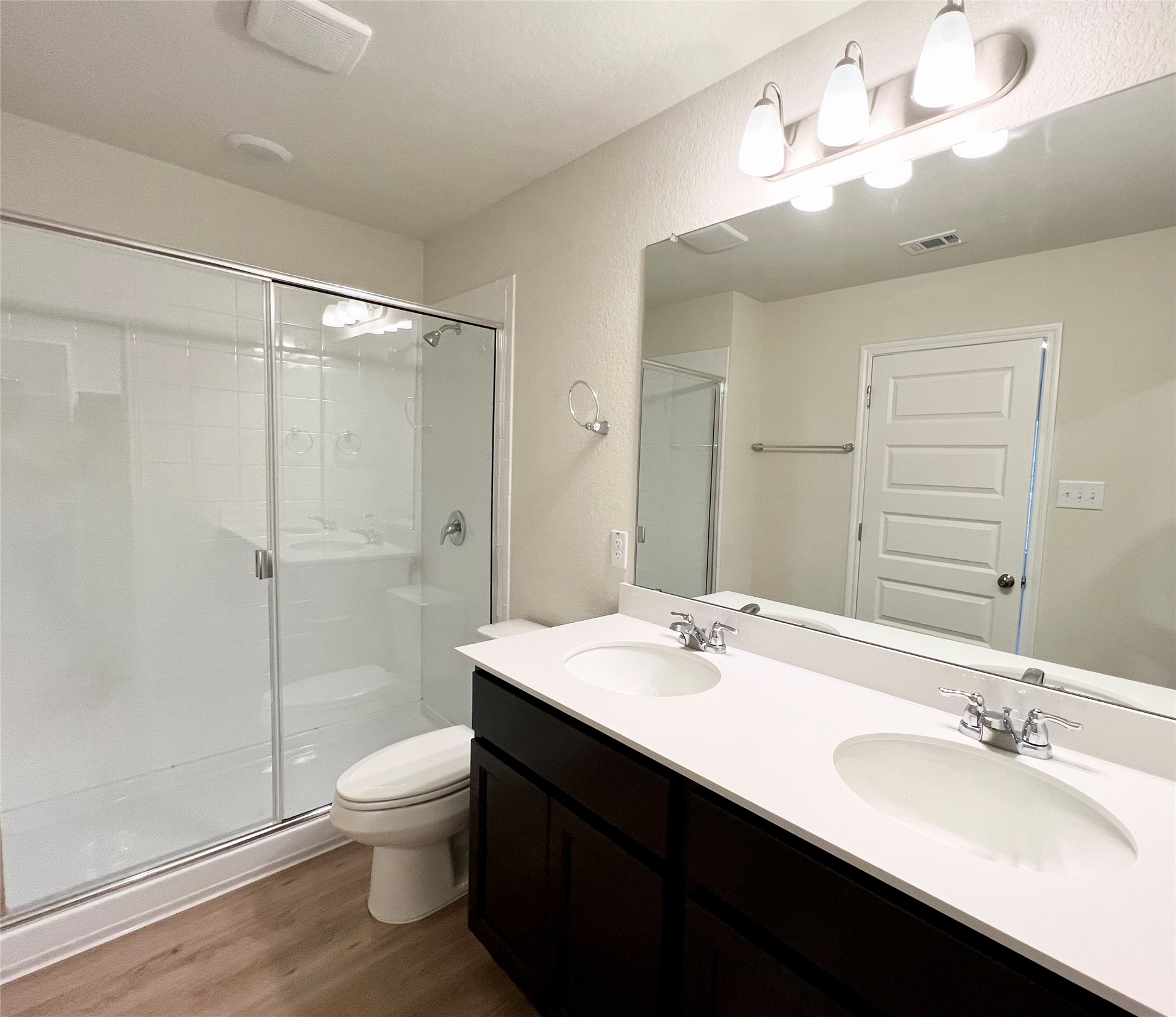 325 Alcatraz Loop Jarrell, TX 76537 - Photo 5 of 16 Full bath with double vanity, a stall shower, dark wood-type flooring, and a textured wall