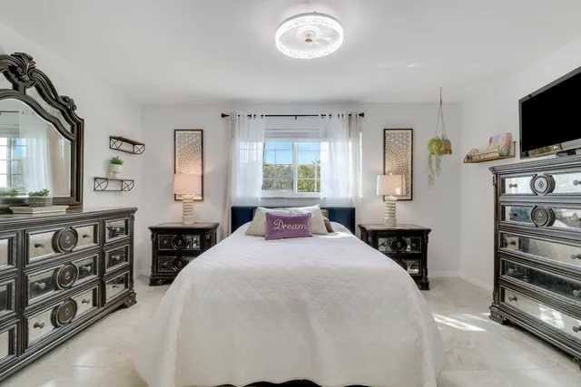 a bedroom with a bed and a flat tv screen on the dresser