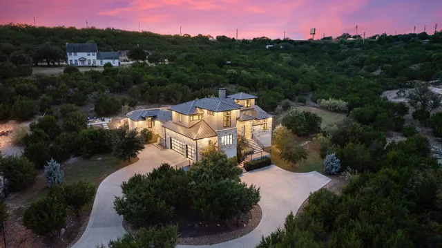 an aerial view of residential houses with outdoor space and trees