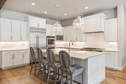 a kitchen with stainless steel appliances granite countertop a table chairs sink refrigerator and cabinets