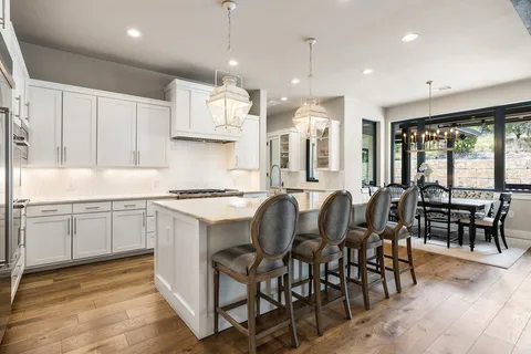 a kitchen with stainless steel appliances granite countertop table chairs sink and stove top oven