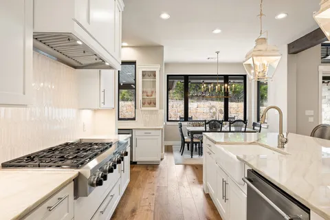 a kitchen with a stove a sink a refrigerator and wooden floor